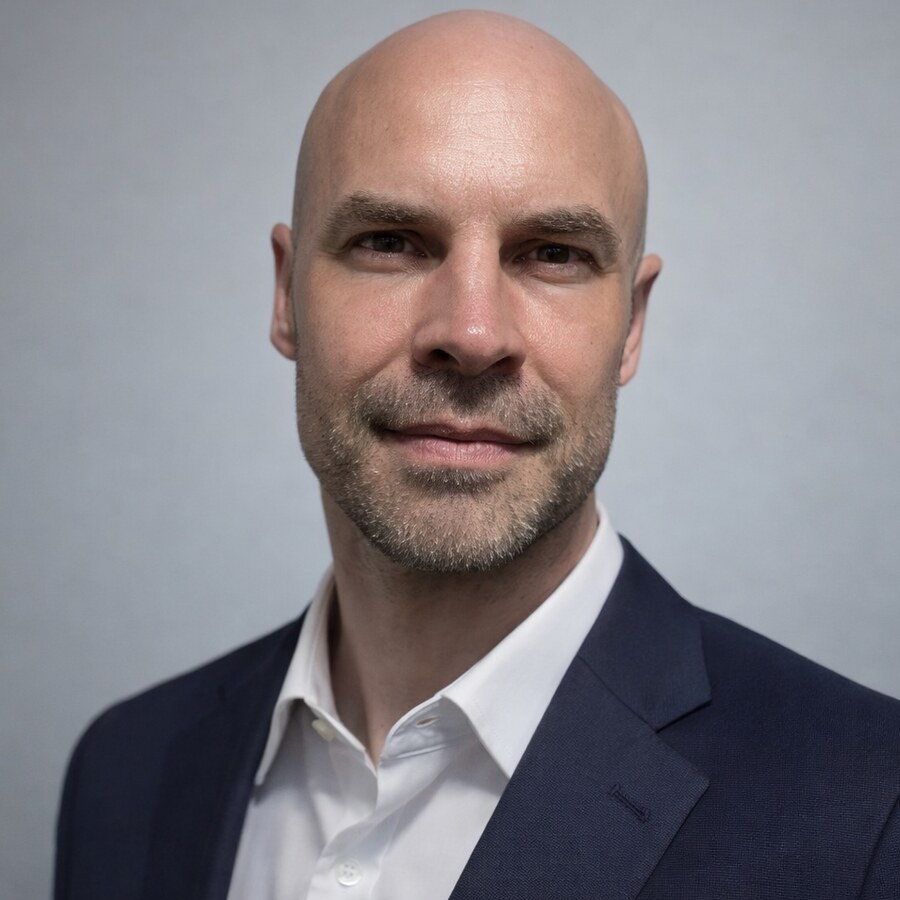 Jon Fila in a navy blazer and white shirt against a gray background
